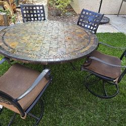 Stone patio table with 4 swivel and rocking chairs.