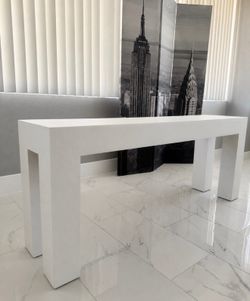 Textured white console table is constructed with a Parsons-style silhouette.