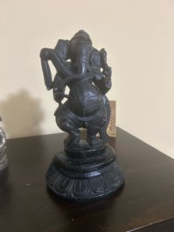 handcrafted black stone statue of Lord Ganesha in a dynamic dancing pose, set upon an ornate lotus-carved circular pedestal. [1] (https://www.exoticin