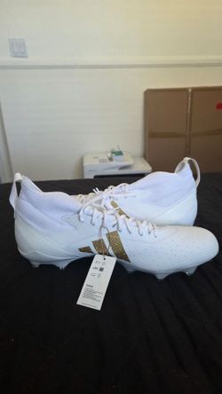 Size 17
New adidas football cleats are white with gold accents. These synthetic and textile cleats have a mid-top design and a cleated outsole for tra