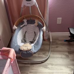 Compact baby swing with a wooden toy bar.