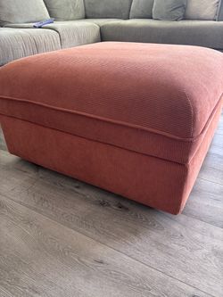rust-orange corduroy-upholstered ottoman (footstool) with a boxed, tailored base design.