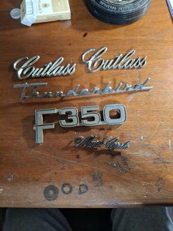 VINTAGE AUTO EMBLEMS,  THUNDERBIRD,  CUTLASS, MONTE, F350, AND FAIRLANE 500. ALL IN GOOD CONDITION,  NEEDS CLEANING 