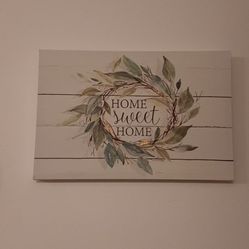 Wall art with 'Home Sweet Home' text and leaf design.