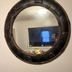 Large round mirror with black and gold frame and elephant designs