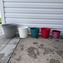 Set of 5 plastic plant pots in different sizes and colors.