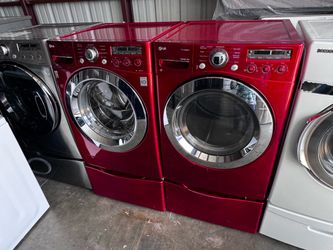 Red front LG washer and front load LG dryer electric high efficiency with pedestals.