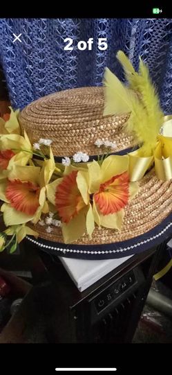 Boater hat with a dark ribbon, a pearl-like trim, and a bouquet of yellow & peach flowers & feathers