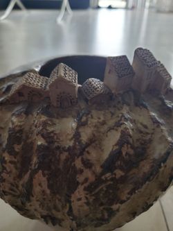 Heavy glazed clay brown vase has small houses village on rim