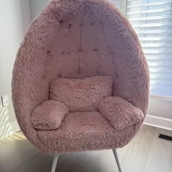 Pink furry egg chair with pillows