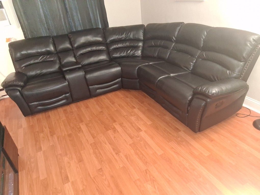 Black leather power reclining sectional sofa with a console and cup holders.