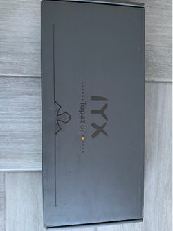 New IYX Topaz 87 mechanical keyboard has a white and pink color scheme. This 87-key layout keyboard is in its original packaging with protective foam 