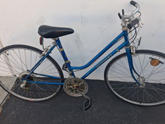 vintage Nishiki step-through road or touring bicycle featuring a metallic blue steel frame and upright handlebars.Key features include a multi-speed d