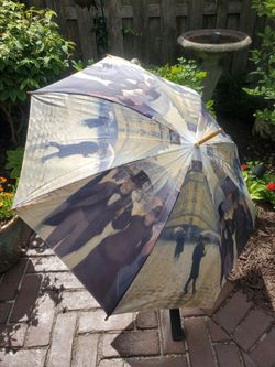 Vintage umbrella with wooden handle and wood tips around the outer edge.  With a walking through Paris theme.