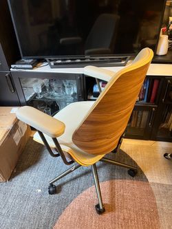 mid-century modern ergonomic office chair featuring a stylish curved wood back and cream-colored faux leather upholstery.