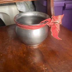The object in the image is a small metal bowl decorated with a red ribbon.