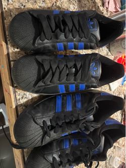 2 Adidas Superstar II shoes in a black and blue colorway.
