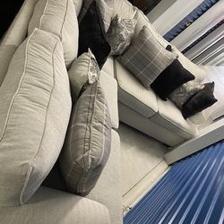 L shaped sectional couch in light beige with black and grey pillows