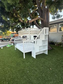 White full-over-queen bunk bed featuring separate steps and a built-in bookcase on the side; includes both mattresses.