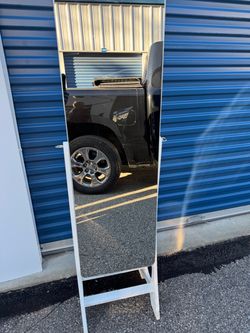 white standing jewelry armoire with a full-length mirrored door