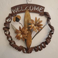 Metal welcoming wreath with flowers and a lady bug.