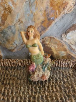 "Syrens of the Sea" resin mermaid figurine featuring glitter accents and a coral base.