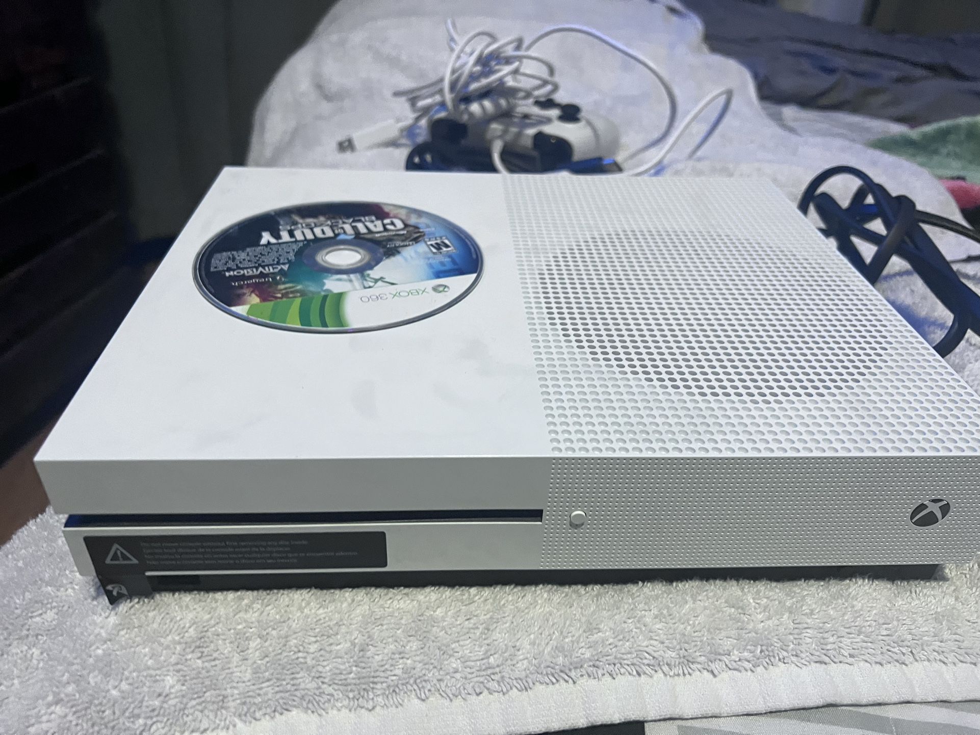 Microsoft Xbox One S console with a physical game disc, specifically Call of Duty: Black Ops, inserted.