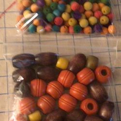 Two bags of assorted sizes, colors, and shapes of wooden beads new in package