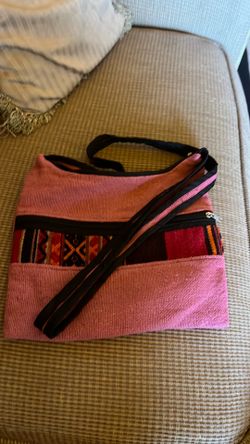 This is a pink crossbody bag featuring a band of traditional Peruvian-style patterned fabric across the front.