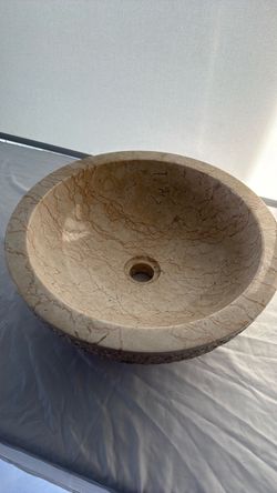 round, gold-beige natural marble vessel sink with a polished surface