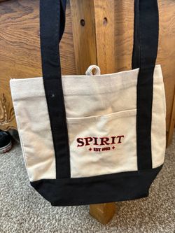 beige and black Spirit Halloween Mini Tote Bag featuring bold red "SPIRIT EST. 1983" lettering on the front pocket
