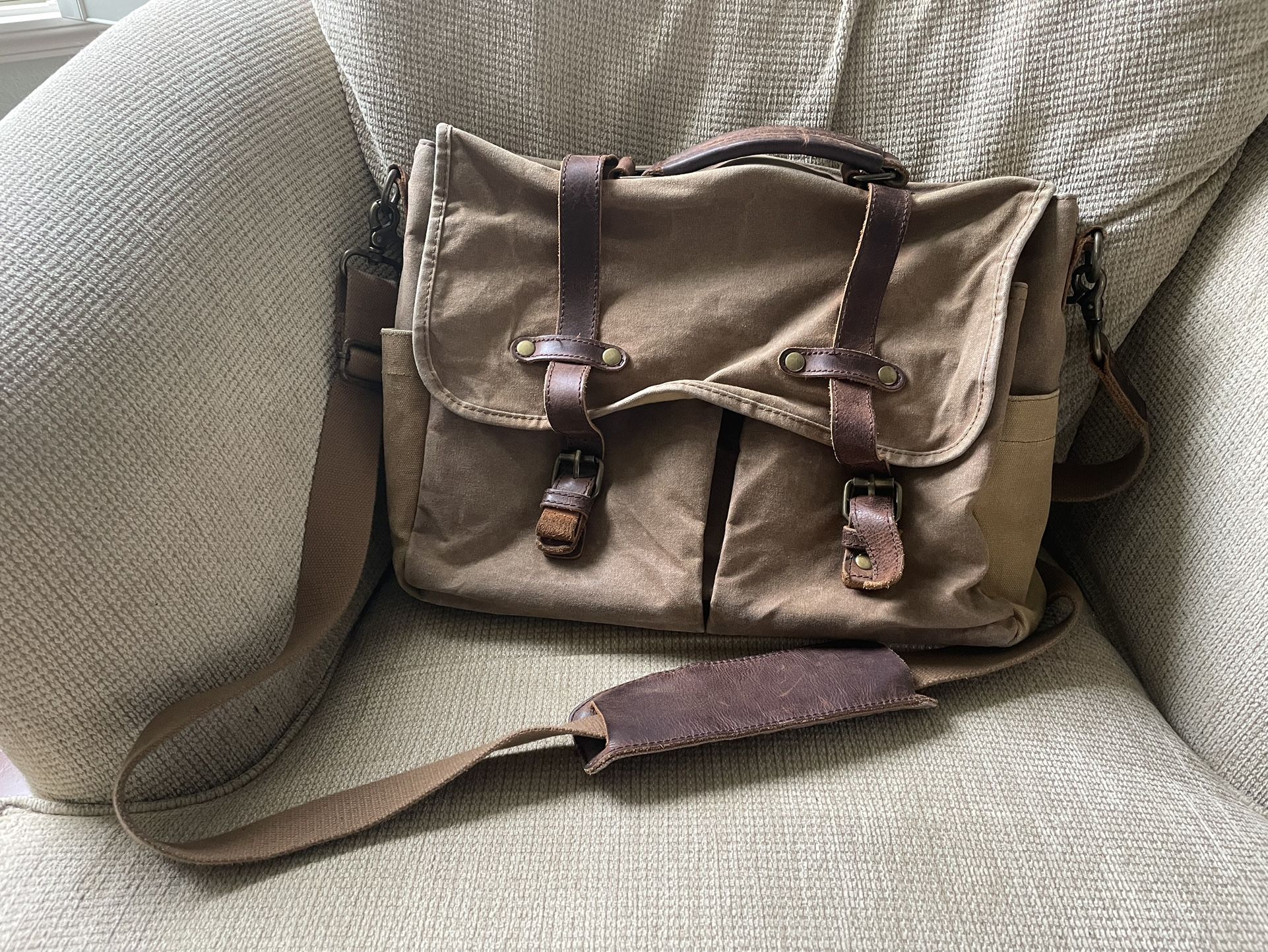 Brown canvas messenger bag with leather straps.