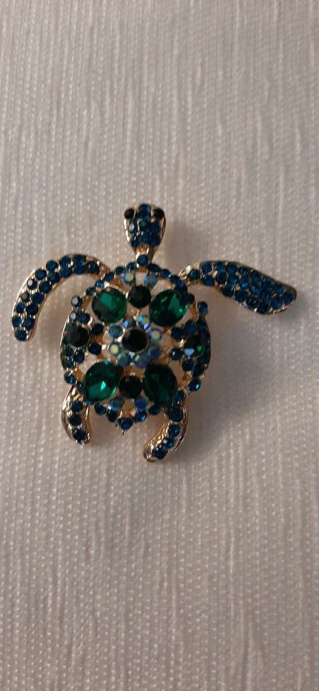 Turtle-shaped brooch gold tone with green stones.