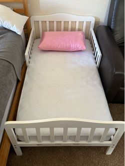 White wooden toddler bed with mattress
