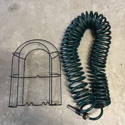 Coiled garden hose set featuring a self-retracting green hose and a wire storage rack