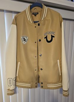True Religion varsity jacket in tan and Cream . Features bold logo patches and button-up front. Unisex.