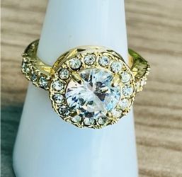 Elegant gold-tone halo ring featuring a large white crystal center and sparkling white crystal accents. The gold-tone band adds warm shine and refined