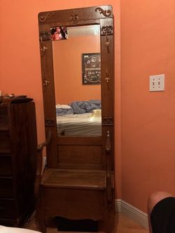 antique oak hall tree featuring a central vertical mirror and a lift-top storage bench seat at the base.