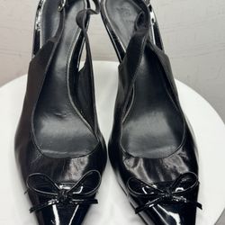 Black leather women's high heel shoes with a strap at the back and a patent leather bow at the front