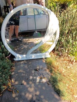 +2                    This white seashell-shaped mirror is a vintage 1980s Art Deco revival piece, often made of ivory lacquered wood or plastic