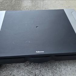 Sturdy Fellowes monitor stand. Gray and black design. Has some storage drawe underneath. Approx 20 inches wide, about 14 inches deep and 4 inches heig