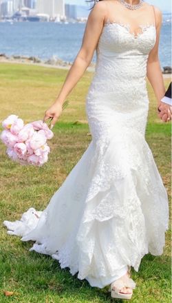 Ivory lace fit-and-flare mermaid wedding gown with an illusion sweetheart neckline and cascading ruffle skirt.