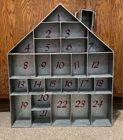 Countdown to Christmas house-shaped galvanized metal advent calendar with 24 numbered cubbies and a small chimney