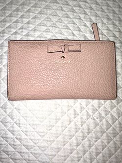 The Kate Spade New York Pershing Street Stacy pink handbag in grained leather stands out for its delicate bow detail and gold logo on the front.