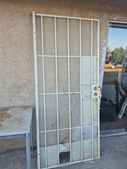 white metal security screen door featuring decorative scrollwork and a galvanized steel mesh screen.