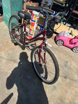 Burgundy Raleigh Venture comfort bike has a step-through aluminum frame. This bicycle is equipped with a padded Avenir seat and a Shimano drivetrain. 