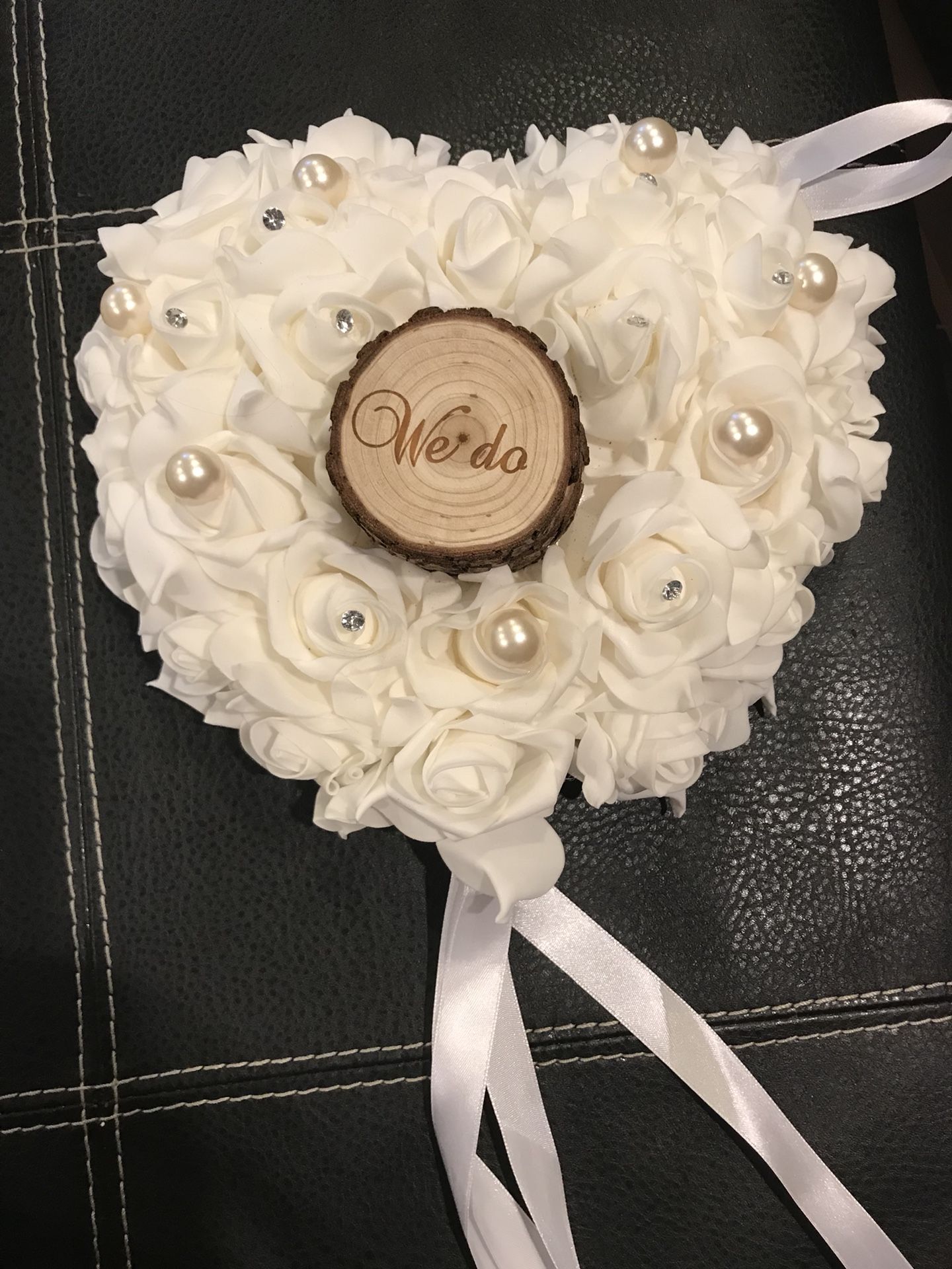 White foam rose wedding ring barer pillow with log in the middle.