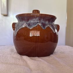 This vintage lidded bean pot is identified as a product by Hull Pottery, likely featuring their signature brown drip glaze