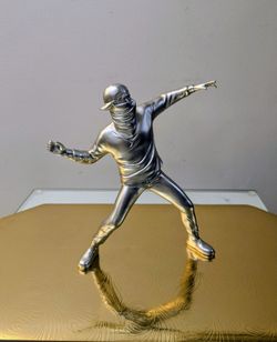 The silver-colored resin figurine is a replica of Banksy's famous "Flower Thrower" statue.