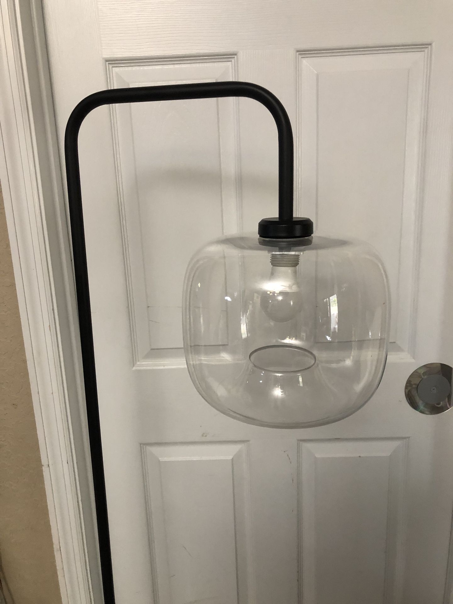 Project 62 Glass Globe Floor Lamp, which features a similar black industrial arch design with a round glass shade and marble base